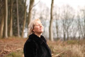 Anna står i en nøgen skov og vender ansigtet mod himlen